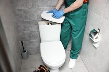 Plumber repairing toilet bowl in water closet, closeup