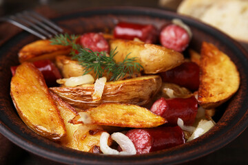 Delicious baked potato with thin dry smoked sausages and onion in bowl, closeup