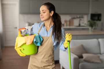 Content woman with cleaning equipment ready for chores