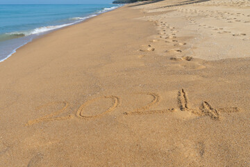 Fototapeta na wymiar 2024 written in the sand on the beach - Happy New Year