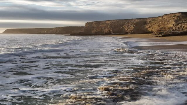 Aerial coverage of waves and cliffs at Davenport Beach at sunset