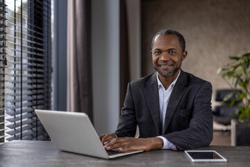 Professional african american businessman smiling at camera with laptop