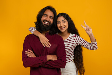 Cheerful loving young hindu couple bonding on yellow background