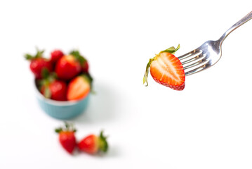Half of the red strawberries on the fork. Strawberries on a white background.