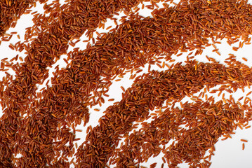 Brown rice scattered in an arc on a white background. Background with a pattern of brown long rice