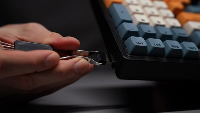 Cropped shot of unrecognizable man using special clip insert USB receiver after connect keyboard wirelessly. Male prepping new mechanical gaming RGB keyboard with stylish keycaps ready to go, closeup.