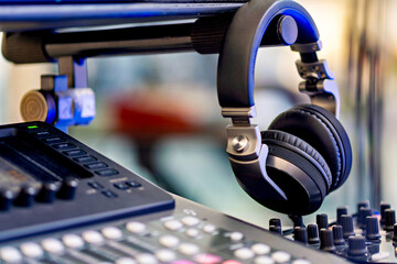 Pair of headphones sitting on top of sound mixing desk next to remote control