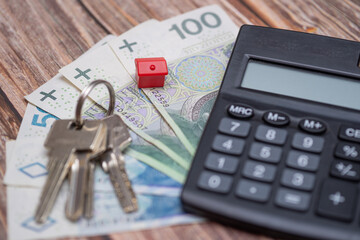 close-up of Polish money next to a calculator, keys and a small house. A concept showing the housing market in Poland