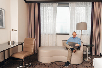 man in casual business attire working on a laptop in a hotel room