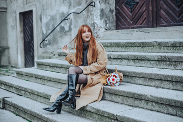 A trendy red hair woman sitting on grungy stairs on a city street.