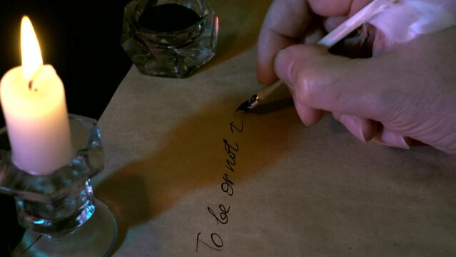 Quill pen in hand, ink and writing text by candlelight. A man writes with a quill pen.