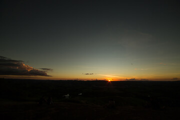 Por do sol com céu vermelho, amarelo, e sombras fortes.