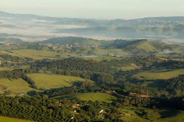 Fototapeta na wymiar Serras cobertas com névoa, vegetação e céu azul. 