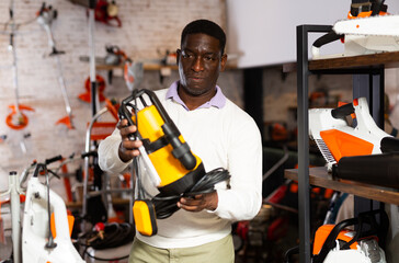 African-american man choosing drainline pump in gardening tools shop.