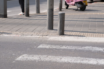 Urban street scene with pedestrian, bollard, and pink scooter in the background in Tel Aviv