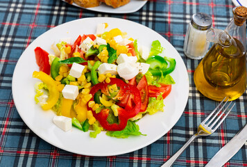 Easy everyday salad of lettuce, green, red and yellow sweet peppers, tomato, corn and soft cheese