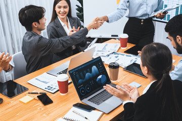 Diverse coworker celebrate with handshake and teamwork in corporate workplace. Happy business...