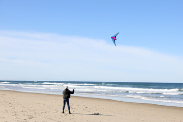 Vacation with teenagers flying stunt kites on the beach along the Oregon Coast,  Blue sky with clouds, waves and sand in the background.