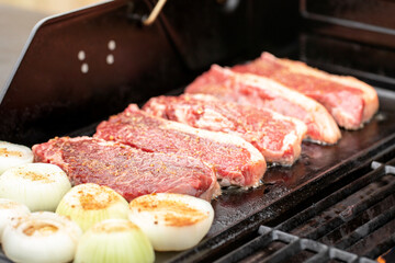 Beef steaks and onions sizzling on the grill, perfect for a delicious meal