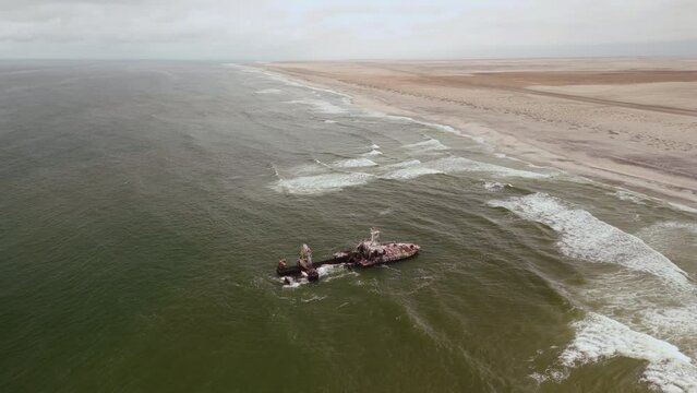Decaying shipwreck close to the desert, postapocalyptic scene.