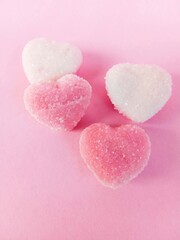 heart shaped candies. a group of pink and white heart-shaped chewy candies on a pink background. chewy candy sprinkled with granulated sugar. sweet and chewy