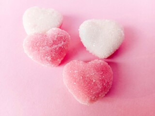 Obraz premium a group of pink and white heart-shaped chewy candies on a pink background. chewy candy sprinkled with granulated sugar. sweet and chewy 
