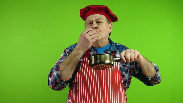 Senior gourmet chef smelling food aroma from stewpan enjoying of smell of food.