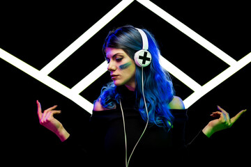 A woman with vibrant blue hair wearing headphones against abstract light shape made of white neon led