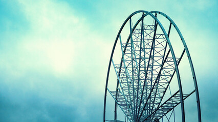 Big city ferris wheel. Blue and cloudy sky background. Much copy space.