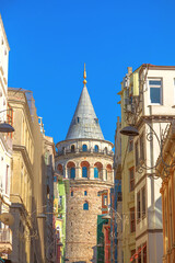 The ancient Galata tower stands tall in Istanbul Galata district, framed by ancient buildings against a clear blue sky of Turkey.