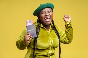 Portrait overjoyed stylish African woman holding passport with frights ticket isolated on...