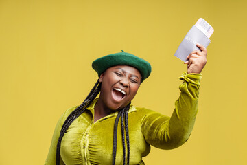 Portrait happy stylish African American woman holding passport with flight tickets isolated on background. Overjoyed tourist  waiting for travel. Vacation concept 