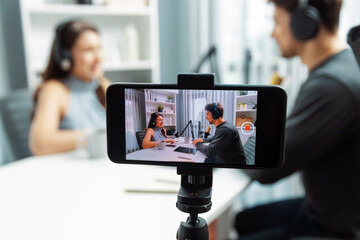 Focus on smartphone recording with blurry host channel broadcasters background making advice...