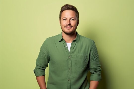 Portrait of a handsome young man in a green shirt on a green background