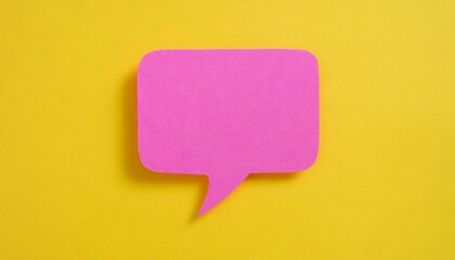 Pink paper cut out speech bubble shape set on yellow paper background.