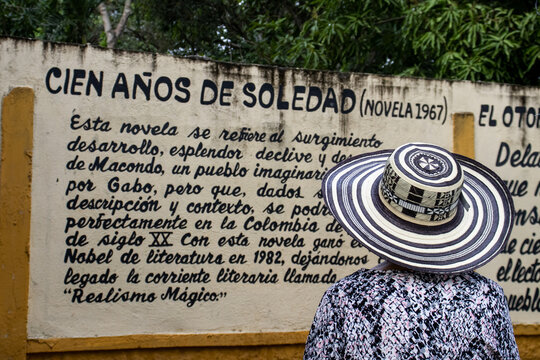 ARACATACA, COLOMBIA - FEBRUARY 2, 2024: Senior woman tourist at the Macondo Linear Park in Aracataca. Text describing One Hundred Years of Solitude by the Literature Nobel Prize Gabriel Garcia Marquez