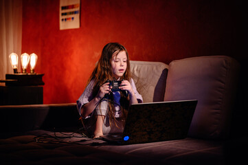 Intense focus is etched on a young girl's face as she maneuvers a game controller, deeply immersed...