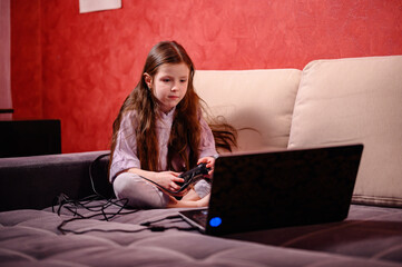 A young girl is deeply focused while playing a video game, her expression a blend of concentration...