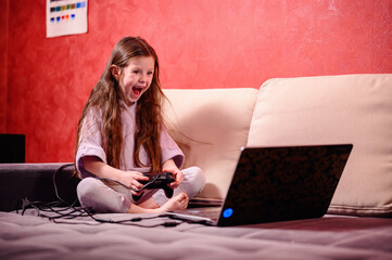A young girl's exuberant reaction lights up the room as she celebrates a win, game controller in hand, encapsulating the thrill and joy of gaming success © Иванна Емельянова