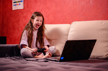 A young girl's exuberant reaction lights up the room as she celebrates a win, game controller in...
