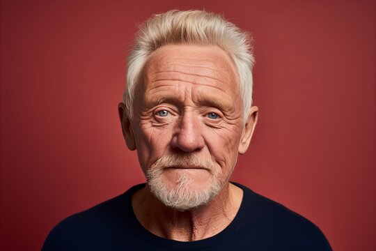 Portrait Of An Elderly Man On A Red Background. Studio Shot.