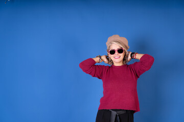Pretty woman smiling with red cap and glasses on a blue background.