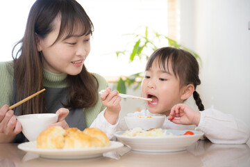 一緒のご飯は美味しいね！の表情をする母と娘の親子　の食事シーン