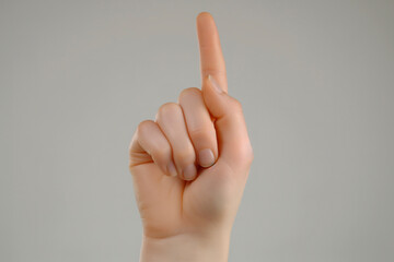 Close-up shot of a hand holding up a peace sign gesture against a white background.