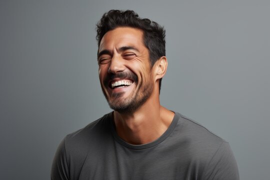 Portrait of a handsome young man laughing and looking up against grey background