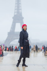 Young beautiful happy woman in red French beret in Paris, France against Eiffel Tower.  European tourism and travels to the capital cities