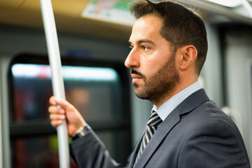 Businessman hanging to a pole in a train in the subway