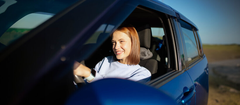 young woman driver driving a car on a sunny day.