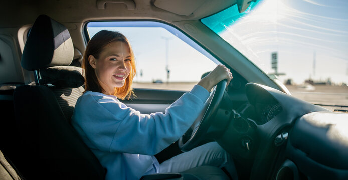 A beautiful woman driving a car in summer smiles successfully