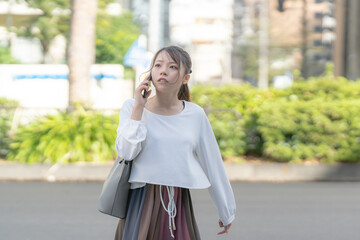 A young Japanese woman in her 20s walking while talking on a smartphone in the streets of Nagoya...